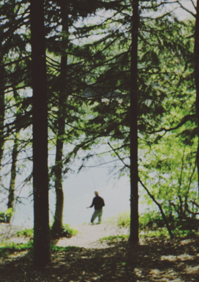 Photographie d'un pécheur en pleine forêt devant un lac.